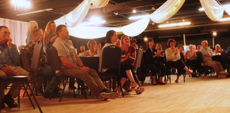 People sitting and clapping in a banquet hall