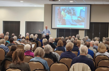 A large group of people listening to a presentation.