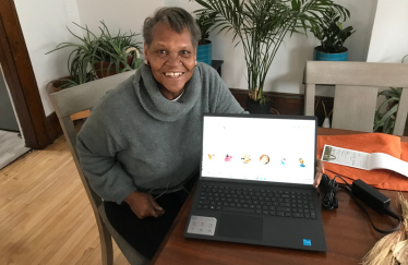 A woman smiling with her laptop in her home.